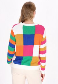 Maglione a maglia multicolore caratterizzato da grandi blocchi in verde, blu, arancione, rosa e giallo, con strisce bianche sulle maniche e bordo a costine.