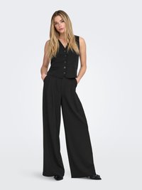 Black vest with a V-neck and four buttons, paired with wide-leg black trousers. Both garments feature a smooth fabric texture.