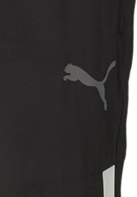 Schwarze Sporthosen mit einem dezenten grauen Puma-Logo, einer glatten Textur und einem paneelierten Design, akzentuiert durch weiße Streifen.