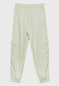 Pantalon beige clair avec cordon de serrage, taille et poignets élastiques, avec deux poches cargo latérales à rabat.