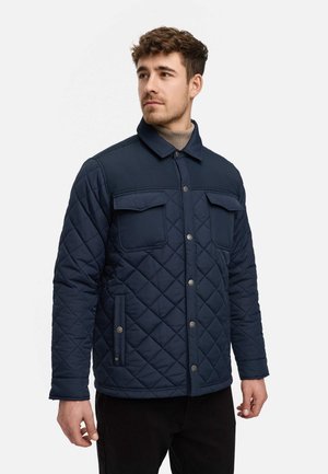 Chaqueta acolchada navy con patrón de diamantes, botones a presión, dos bolsillos en el pecho y cuello con solapa. Tejido suave con una textura blanda.