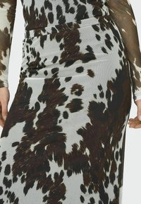 Figurbetontes Kleid aus glattem, dehnbarem Stoff mit grauem Hintergrund und großen, unregelmäßigen schwarz-braunen Tiermusterungen.