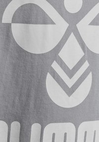 Tejido gris con grandes patrones geométricos blancos, incluyendo formas circulares y diamantes, con una superficie texturizada y un diseño moderno.