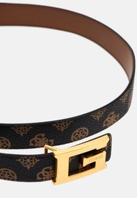 Cintura a strisce nere e marroni realizzata in materiale sintetico, caratterizzata da una fibbia in metallo color oro con la scritta "GUESS" incisa. Texture liscia.