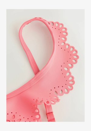 Růžová podprsenka s vlnkovým okrajem, zdobená výřezovými květinovými vzory, hladkým povrchem, nastavitelnými ramínky a vyztuženým pásem.