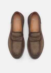 Mocasines de ante marrón con punta redondeada, costuras decorativas y parte superior de estilo mocasín. Plantilla de cuero suave, suela texturizada.