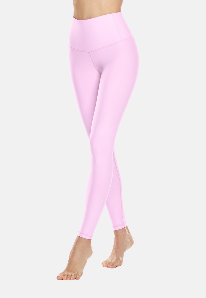 Růžové legíny s vysokým pasem vyrobené z elastické tkaniny, s hladkým povrchem a prodlouženým designem nohavic, vhodné pro aktivní nošení.