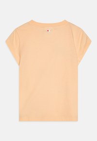 Lühikeste varrukatega, heledast virsikuvärvi T-särk ümarate kaelustega ja väikese logoga taga. Pehme materjal, mugav lõige ja sirge allaäär.