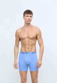 Vaaleansiniset boxerit, joissa on kuvioitu sininen Nike-vyötärö. Kangas näyttää sileältä ja joustavalta, suunniteltu mukavuutta ja istuvuutta varten.