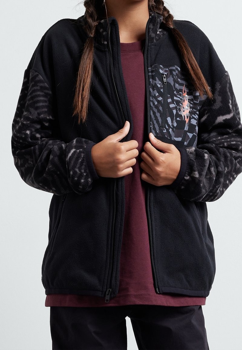 Veste en polaire noire avec manches à motif, fermeture éclair intégrale et petite poche ornée d'un design géométrique aux tons sombres.