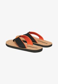 Zwarte en oranje flip-flops met een kurken voetbed, stoffen banden en rubberen zolen, met het "Superdry"-logo op de binnenzool.