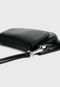 Zwarte leren polsband clutch met zilveren sluiting en afneembare schouderband op een witte achtergrond.