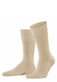 Calcetines de tripulación nude con una textura suave, puño acanalado y puntera reforzada. El nombre de la marca "FALKE" está impreso en la suela.