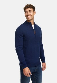 Navy blue rozpinany sweter z dzianiny z prążkowanym kołnierzem, mankietami i dolnym obszyciem. Posiada mały skórzany detal z suwaka.