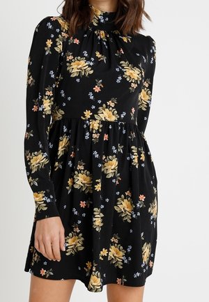 Robe noire à manches longues avec imprimé floral jaune et orange, col montant, taille froncée et un ourlet court au-dessus du genou.