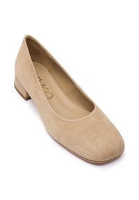 Beige suède platte schoen met een afgeronde neus en lage blokhak. Gladde binnenvoering en minimale details versterken het klassieke ontwerp.