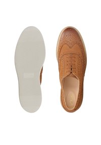 Chaussure brogue en cuir marron avec perforations décoratives, semelle beige montrant les vues de dessus et de dessous sur fond blanc.