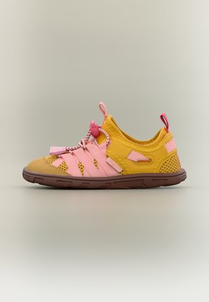 Baskets légères jaunes et roses avec panneaux en mesh, lacets à bride ajustable, et semelle texturée marron, présentées sur un fond neutre.