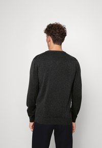 Pull gris foncé à manches longues, col rond, tissu texturé, et poignets et ourlet côtelés, vu de dos.