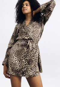 Leopárdmintás rövid köntös selymes anyagból, amely stólakabáttal, hosszú ujjakkal és megkötős derékrésszel rendelkezik, laza sziluettet teremtve.