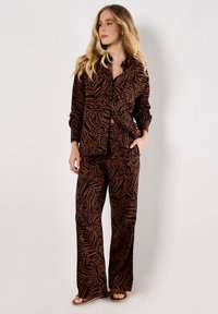 Brown and black leaf-patterned matching set featuring a button-up top and wide-leg pants, made from a soft, lightweight fabric.