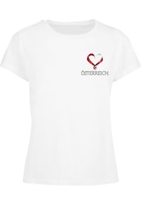 Hvid bomulds t-shirt med et rødt og hvidt hjerte-design ovenover ordet "ÖSTERREICH" i grå. Korte ærmer og rund halsudskæring.
