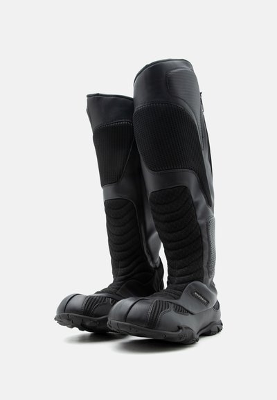 Ψηλές μαύρες μπότες μηχανής με υφασμάτινα προστατευτικά πάνελ και ανθεκτικές σόλες, σχεδιασμένες για ανθεκτικότητα και ασφάλεια.