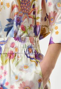 Bloes met bloemenpatroon, voorzien van een zijdezachte textuur, veelkleurig ontwerp met roze, paarse en blauwe bloemen, en een elastische tailleband met plooien.