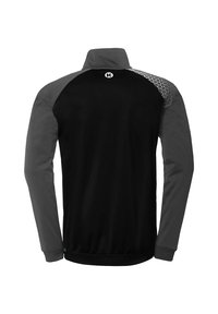 Sort træningsjakke med grå ærmer, høj krave og mønstrede skulderdetaljer. Fremstillet af lette, åndbare materialer.