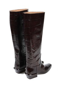 Kozaki do kolan, w ciemnobrązowej skórze, z wzorem wytłaczanym w krokodyle, spiczastym czubkiem i niskim, blokowym obcasem. Gładka faktura z błyszczącym wykończeniem.