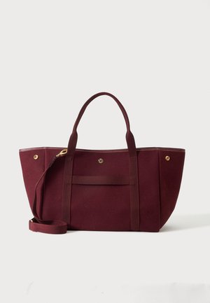 Bolsa tote granate con dos asas, una correa de hombro desmontable y pequeños detalles de botones dorados sobre un fondo liso.