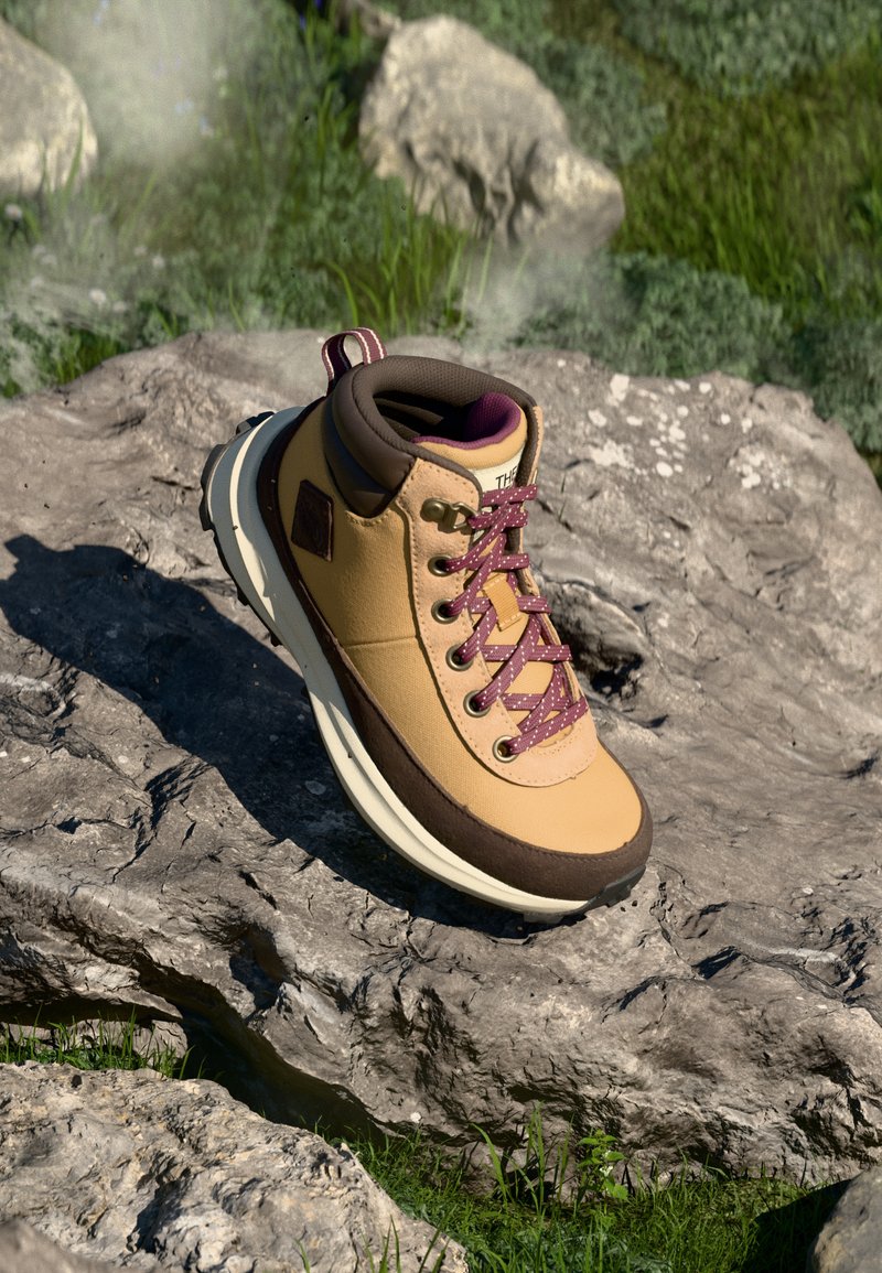 Bota de senderismo con un upper sintético amarillo, acentos marrones y cordones burdeos. Cuenta con un cuello acolchado y una suela de goma texturizada.