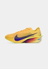 Baskets de course Nike en jaune vif avec un swoosh violet. Présentent un design élégant, un matériau léger et une semelle dégradée dans des nuances de rose et de vert.