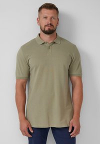 Khaki koszulka polo z kołnierzykiem, krótkimi rękawami i zapięciem na dwa guziki. Gładka, strukturalna tkanina z delikatnym wzorem w paski.