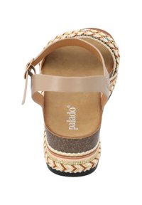 La sandalia de cuña cuenta con una correa beige, una parte superior multicolor trenzada, una suela media texturizada de color marrón oscuro y una plantilla de color beige con un patrón y logotipo.