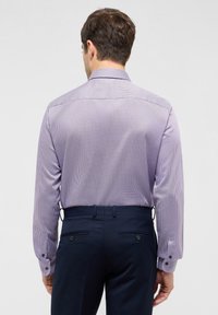 Lange mouw overhemd in lichtpaars met een geometrisch patroon. Voorzien van een klassieke kraag en verstelbare manchetten. Gepaard met donkere broeken.