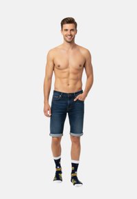 Mörkblå denimshorts i figurnära stil med upplindade fållar. Svarta strumpor med ett färgglatt hamburgermönster och vita detaljer.