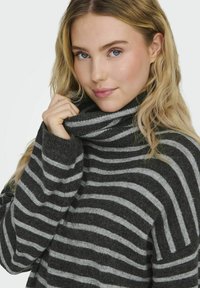 Suéter de cuello alto a rayas grises y negras con una textura suave, que cuenta con mangas anchas y un collar doblado.