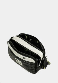 Bolso cruzado en blanco y negro que presenta material brillante, múltiples compartimentos con cremallera y un interior con un patrón gráfico.