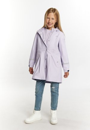 Impermeabile color lavanda chiaro con cappuccio, bottoni a pressione e tasche laterali, abbinato a jeans blu strappati e sneakers alte bianche.