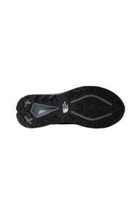 Suela de goma negra con un patrón de tacos multidireccional, con un acento gris y el logo de "The North Face" cerca del talón.