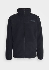 Giacca in pile nera con zip frontale, colletto alto e un piccolo logo sul lato sinistro del petto. Presenta una texture liscia e un design strutturato.