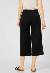 Svarta culotter i mjukt tyg med vid bendesign, elastisk midja och två bakfickor. Sandaler fulländar outfiten.