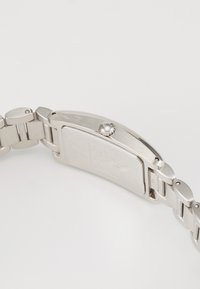 Silver metal wristwatch with a rectangular case, textured surface, and a round crown. Features a linked bracelet and smooth finish.