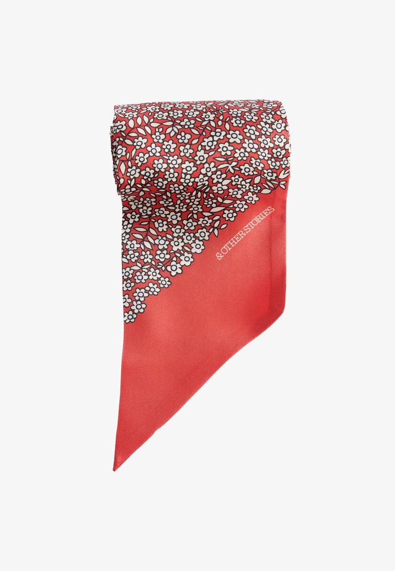 Foulard triangulaire rouge avec un petit motif de fleurs blanches le long d'un bord et le texte «& Other Stories» sur la partie unie.