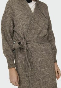 Cardigan marrón de punto con un acabado texturizado, mangas holgadas y un cinturón atado a la cintura.