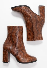 Bottines à imprimé serpent marron avec une finition brillante, dotées d'un talon bloc et d'une fermeture éclair latérale pour un enfilage facile.