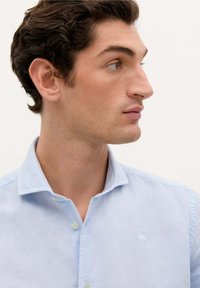 Camicia azzurro chiaro con bottoni, in tessuto di cotone, colletto alla francese, dettaglio logo discreto sul petto, texture liscia, design aderente.