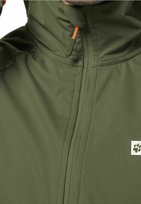 Olivově zelená bunda s plným zipem, vysokým límcem a oranžovým textilním poutkem, s malou nášivkou ve tvaru tlapky.