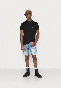 Melna īsroku T-krekls ar kabatu, gaiši zili nodiluši džinsa šorti un melni šņoru zābaki. Izskatu papildina saulesbrilles.